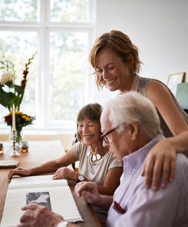 Two older adults and a younger woman enjoying family photographs together